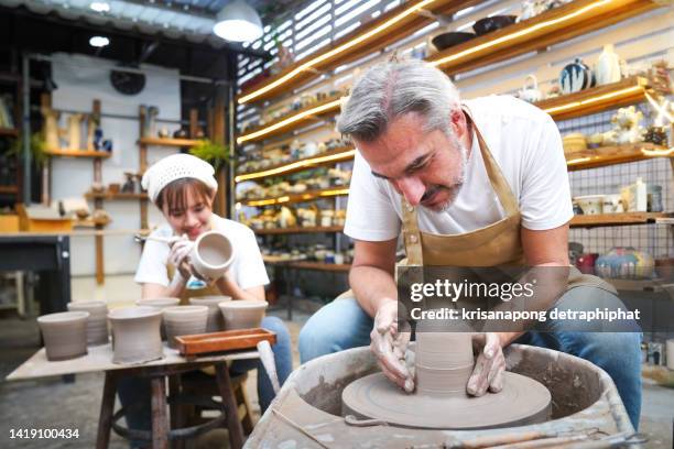 man doing  ceramics with a pottery wheel - senior woman studio stock-fotos und bilder