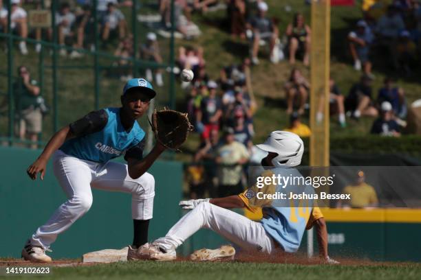 Kama Angell of the West Region team from Honolulu, Hawaii slides safe into third base as Shemar Jacobus of the Caribbean Region team from Willemstad,...