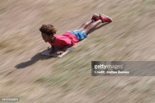 Child slides down a hill on cardboard before the Little League World Series Championship game between the West Region team from Honolulu, Hawaii and...