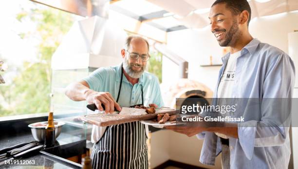 man serving up freshly cooked steak during a barbecue - outdoor kitchen stock pictures, royalty-free photos & images