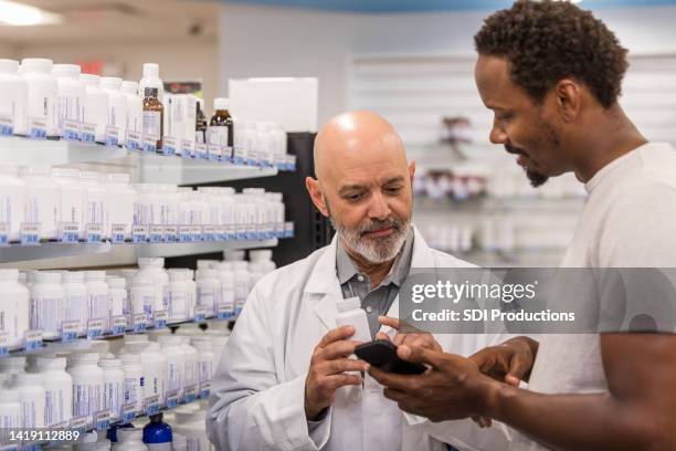 pharmacist and patient read the medication bottle - pharmacist and patient imagens e fotografias de stock