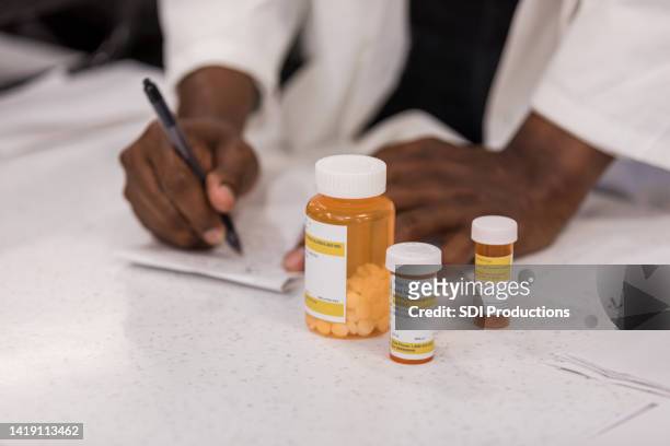 unrecognizable pharmacist fills prescriptions for customer - rx stockfoto's en -beelden