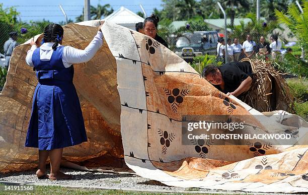 Tongan school children try to lay a carpet of tapa cloth for the hearse carrying the casket of King George Tupou V at Fua'amotu International Airport...