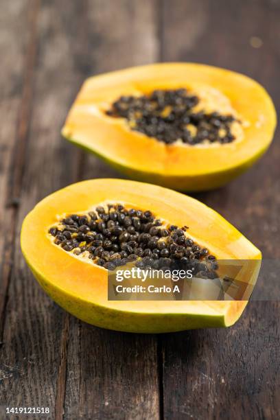 halved papaya on wooden background - papaia foto e immagini stock