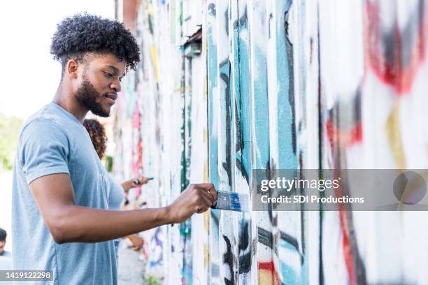 visão de baixo ângulo pintura de estudante masculino sobre grafite - selfless - fotografias e filmes do acervo