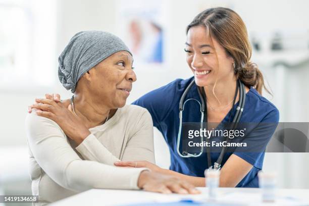 krankenschwester tröstet eine frau mit krebs - oncology stock-fotos und bilder