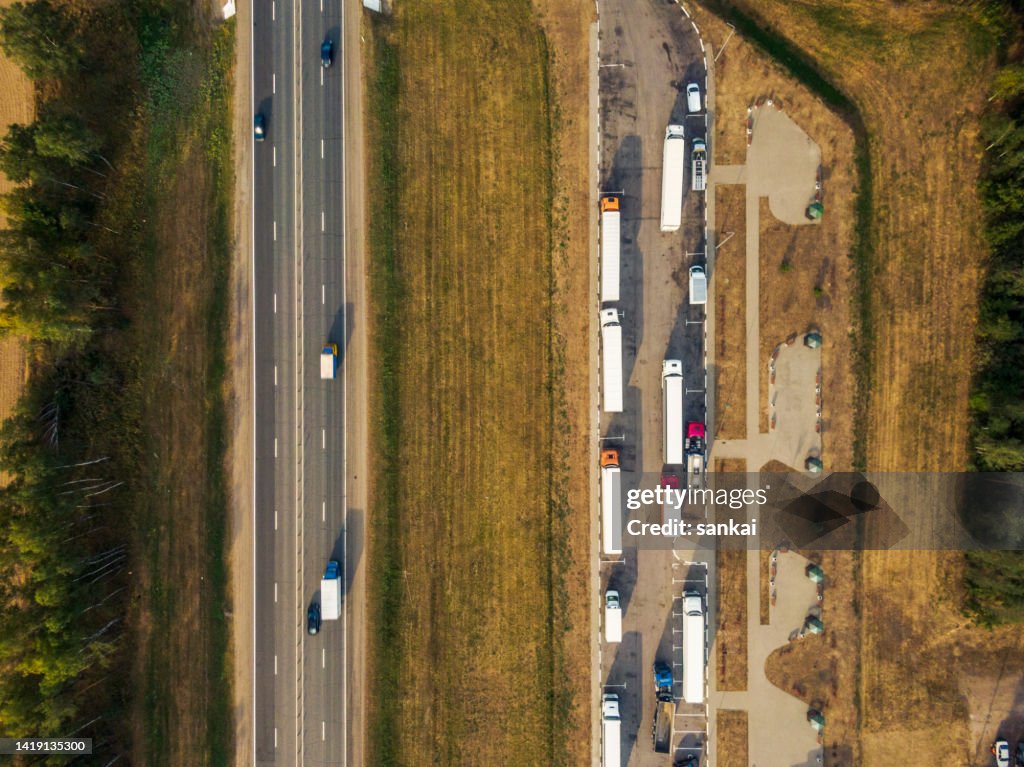 Semi-trucks with trailers at rest parking site near the multiple lane highway