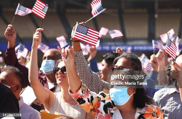 New U.S. Citizens wave American flags after being being sworn in at a naturalization ceremony at Dodger Stadium on August 29, 2022 in Los Angeles,...