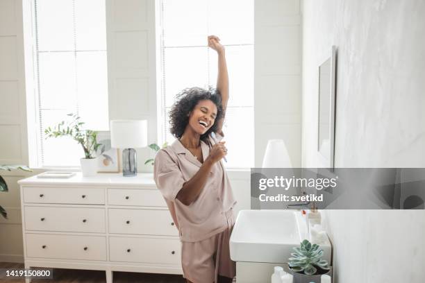 mujer sonriente cepillándose los dientes sanos en el baño - chica bailando en pijama fotografías e imágenes de stock