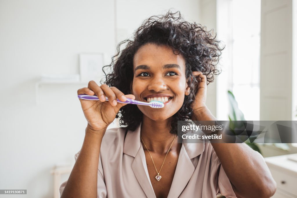Donna sorridente che si lava i denti sani in bagno