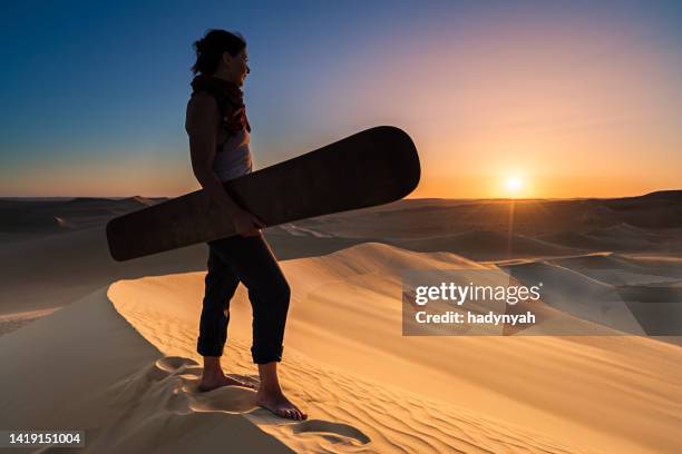 young woman sandboarding in the sahara desert during sunset, africa - sand boarding stock pictures, royalty-free photos & images