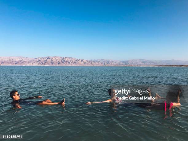 friends floating on water at dead sea - dead sea float stock pictures, royalty-free photos & images