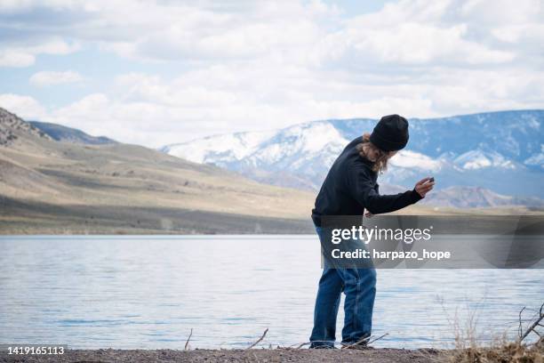 young man throwing a stone in a lake. - skimming stones stock pictures, royalty-free photos & images