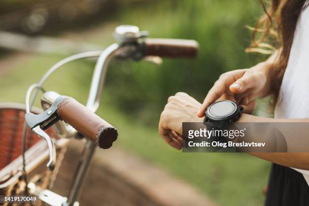 woman push button on smartwatches to start riding bicycle app. gadgets in sport. unrecognizable person - stemdistrict stockfoto's en -beelden
