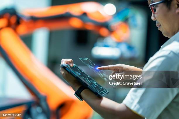 senior engineer working on digital tablet and digitalization display in automated production area . he had development performance for use in robotics arm in process line at night time.production improvement concepts. - performance collective stockfoto's en -beelden