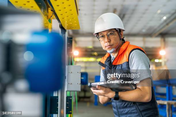 japanese males engineer input sequence of program to strapping machine with digital tablet and digitalization display in automated production line. he had development performance for use in automated machine. production improvement concepts. - aluminium ingots stockfoto's en -beelden