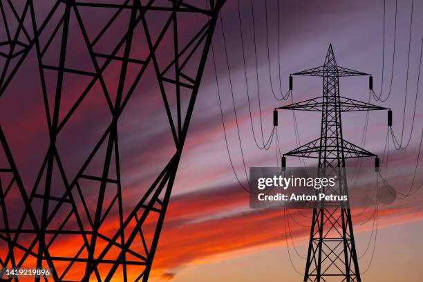 high voltage towers at sunset background. power lines against the sky - pylone-electrique photos et images de collection