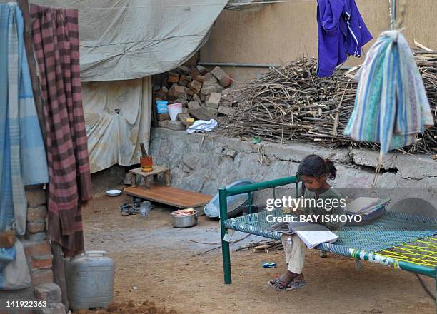 Minority Pakistani Christian child does her homework on a charpoy in the compound of her residence at the Alama Iqbal Colony in Islamabad on March...