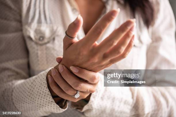 detail of a woman holding her hand in pain caused by a carpal tunnel. - schmerz stock-fotos und bilder
