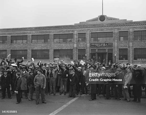General Motors employees, some raising their arms with others waving documents and newspapers, on the picket line outside at the Chevrolet Gear &...