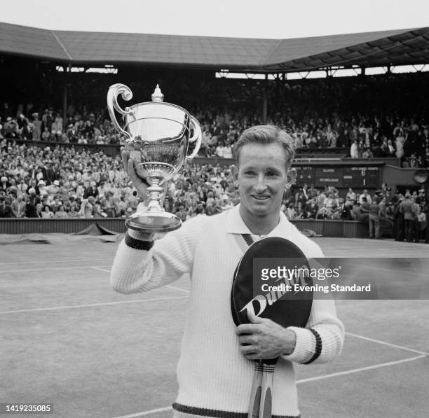 Australian tennis player Rod Laver, a Dunlop tennis racquet under his left arm, his right hand hold the Men's Singles trophy after the final at the...