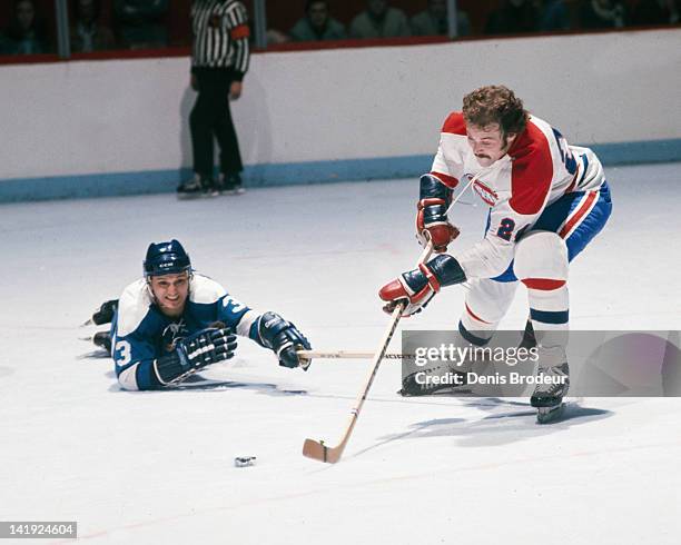 Tim Horton of the Pittsburgh Penguins dives for the puck as Chuck Lefley of the Montreal Canadiens skates towards the net Circa 1970 at the Montreal...