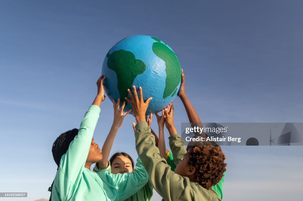 Group of children working together to hold up the world