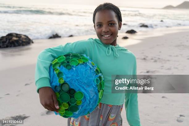 portrait of girl holding large globe on a beach - portrait afrika kind stock-fotos und bilder