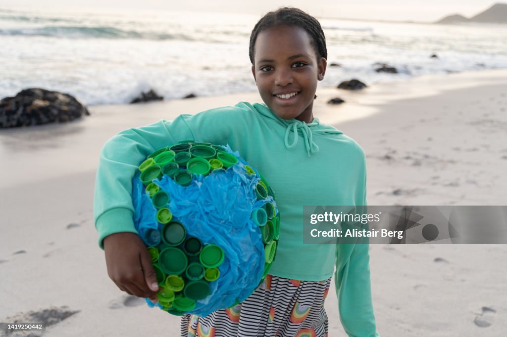 Portrait of girl holding large globe on a beach