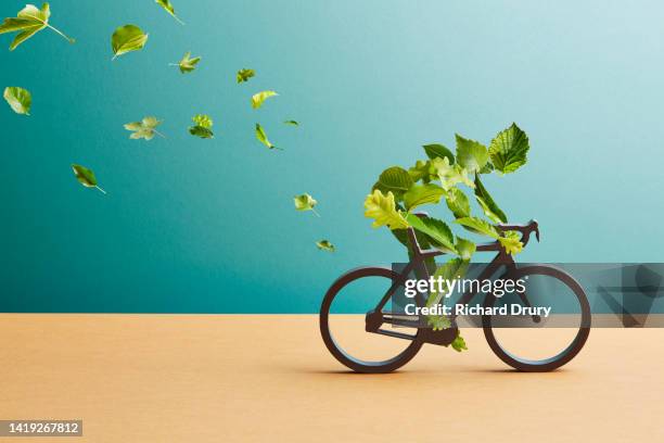 a figure made of leaves rides a bicycle made of leaves - fahrrad grün stock-fotos und bilder