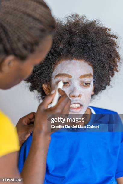 make-up artist is applying white paint around boy's eyes - scary clown makeup stock-fotos und bilder