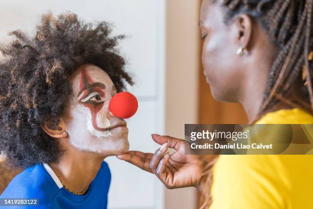 close-up of a woman looks at her son smiling after finishing his makeup and putting on a clown nose - scary clown makeup stock-fotos und bilder