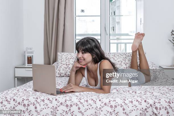 woman lying in bed in front of a laptop computer - aislado stock-fotos und bilder