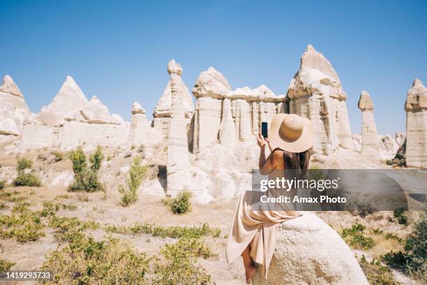 woman taking picture with mobile phone of cappadocia love valley in turkey - cappadocia stock pictures, royalty-free photos & images