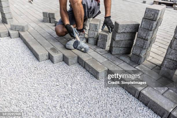 male construction worker paves the area with concrete grey paving tiles. - block paving stockfoto's en -beelden