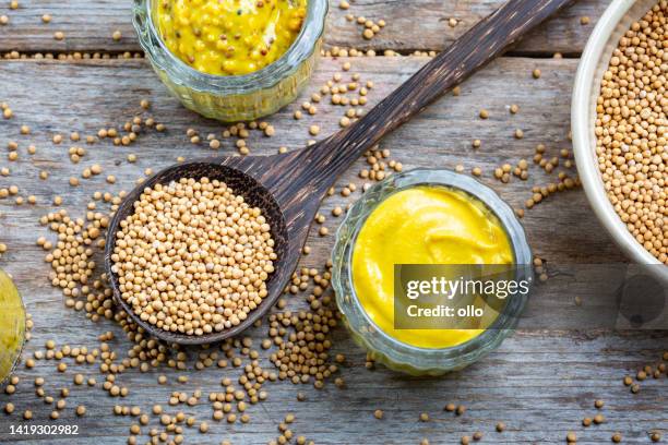 different types of mustard and mustard seeds on a rustic wooden board - mustard stock pictures, royalty-free photos & images