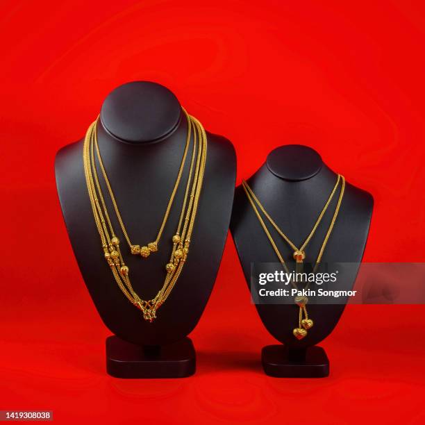 the necklace display stand has a gold necklace on a black background. - open collar stockfoto's en -beelden
