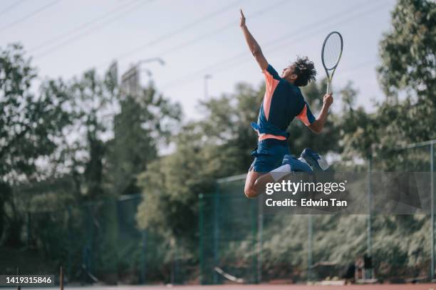 asian chinese male tennis player jumping mid air serving in hardcourt - hardcourt stock pictures, royalty-free photos & images