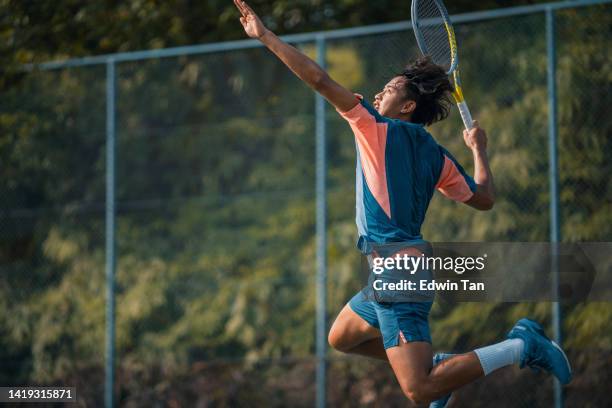asian chinese male tennis player jumping mid air serving in hardcourt - tennis player stock pictures, royalty-free photos & images