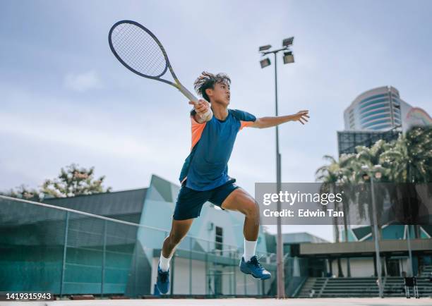 geschickter asiatisch-chinesischer tennisspieler, der in der luft springt und rettet - making a save sports stock-fotos und bilder