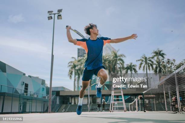 skilful asian chinese tennis player jumping mid air making a save - hardcourt stock pictures, royalty-free photos & images