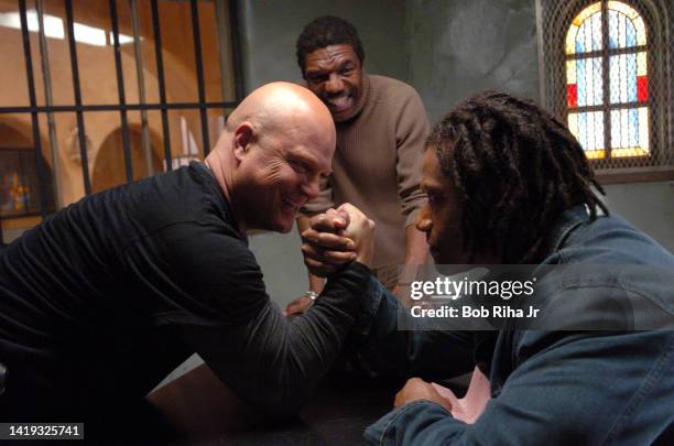 Michael Chilkis playfully arm-wrestles with co-star Greg Eagles while Director Vondi Curtis-Hall watches the action on the set of FX series The...