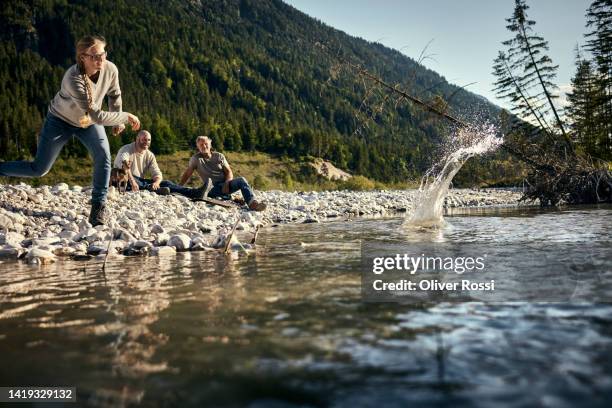 woman with friends at a riverbank skipping stones - skimming stones stock pictures, royalty-free photos & images