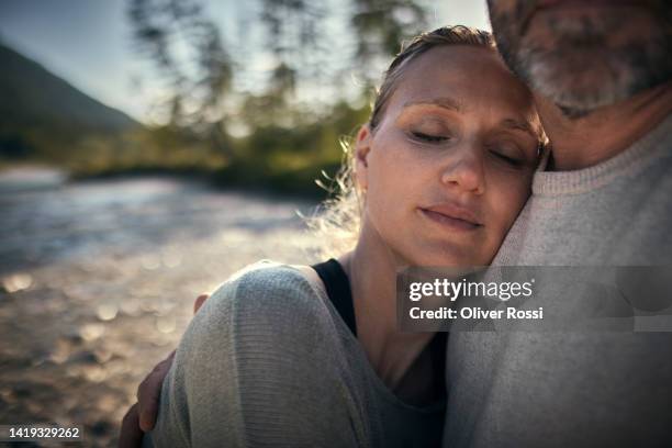 woman with closed eyes leaning against man's shoulder in nature - garantie stock-fotos und bilder