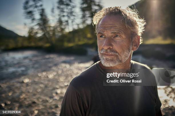 portrait of a mature man at a riverbank at sunset - contemplation outside bildbanksfoton och bilder