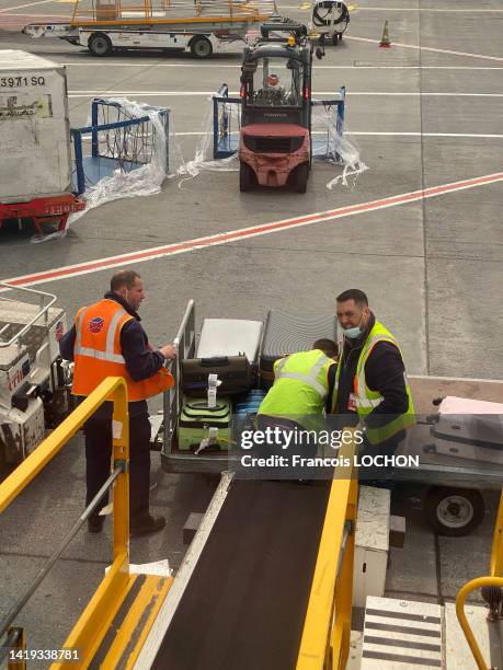Employés de l'aéroport de Roissy CDG chargeant des bagages dans un avion avec un tapis roulant le 30 avril 2021.
