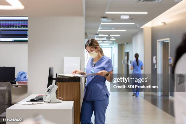 nurse stands at the computer desk - nurses station stock pictures, royalty-free photos & images