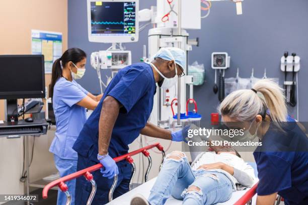 diverse trauma team stabilizes female patient in emergency room - er stock pictures, royalty-free photos & images