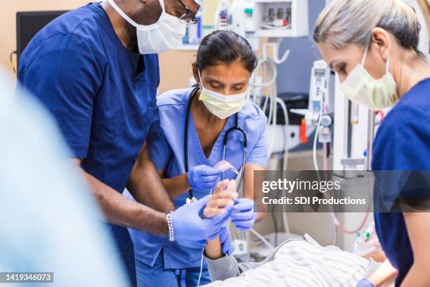 vielfältiges team der notaufnahme arbeitet an nicht erkennbaren patienten - puls oxymeter stock-fotos und bilder