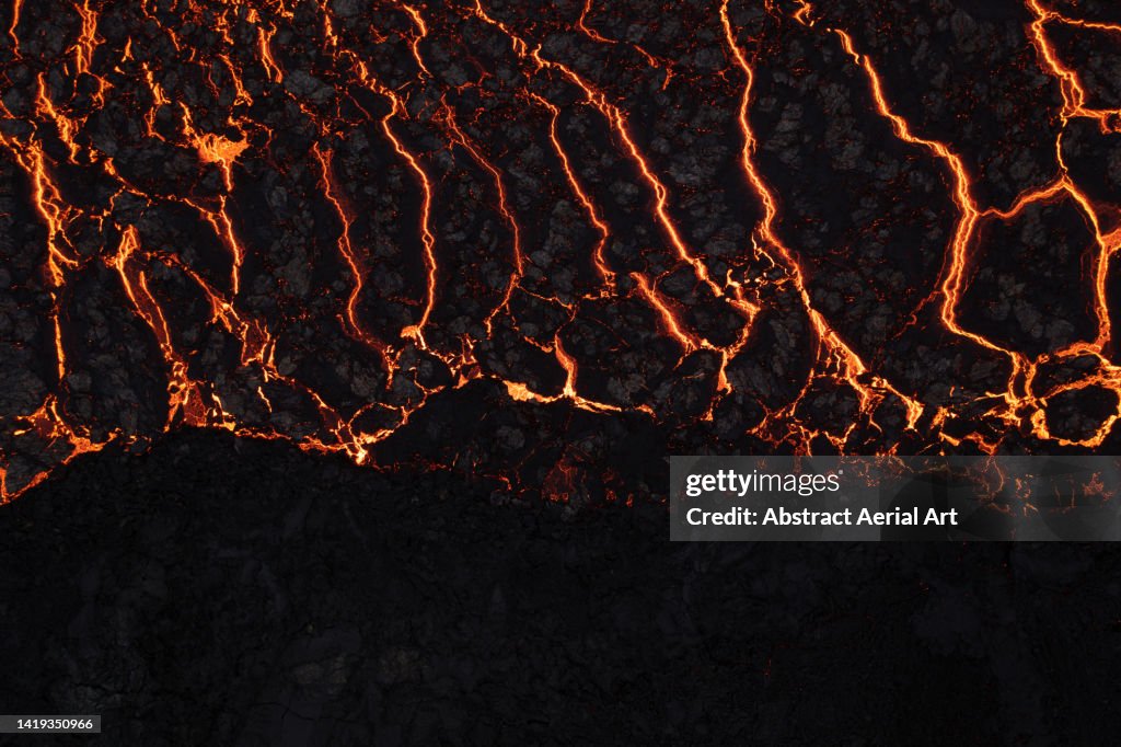 Night time image showing the edge of a glowing lava plain, Iceland
